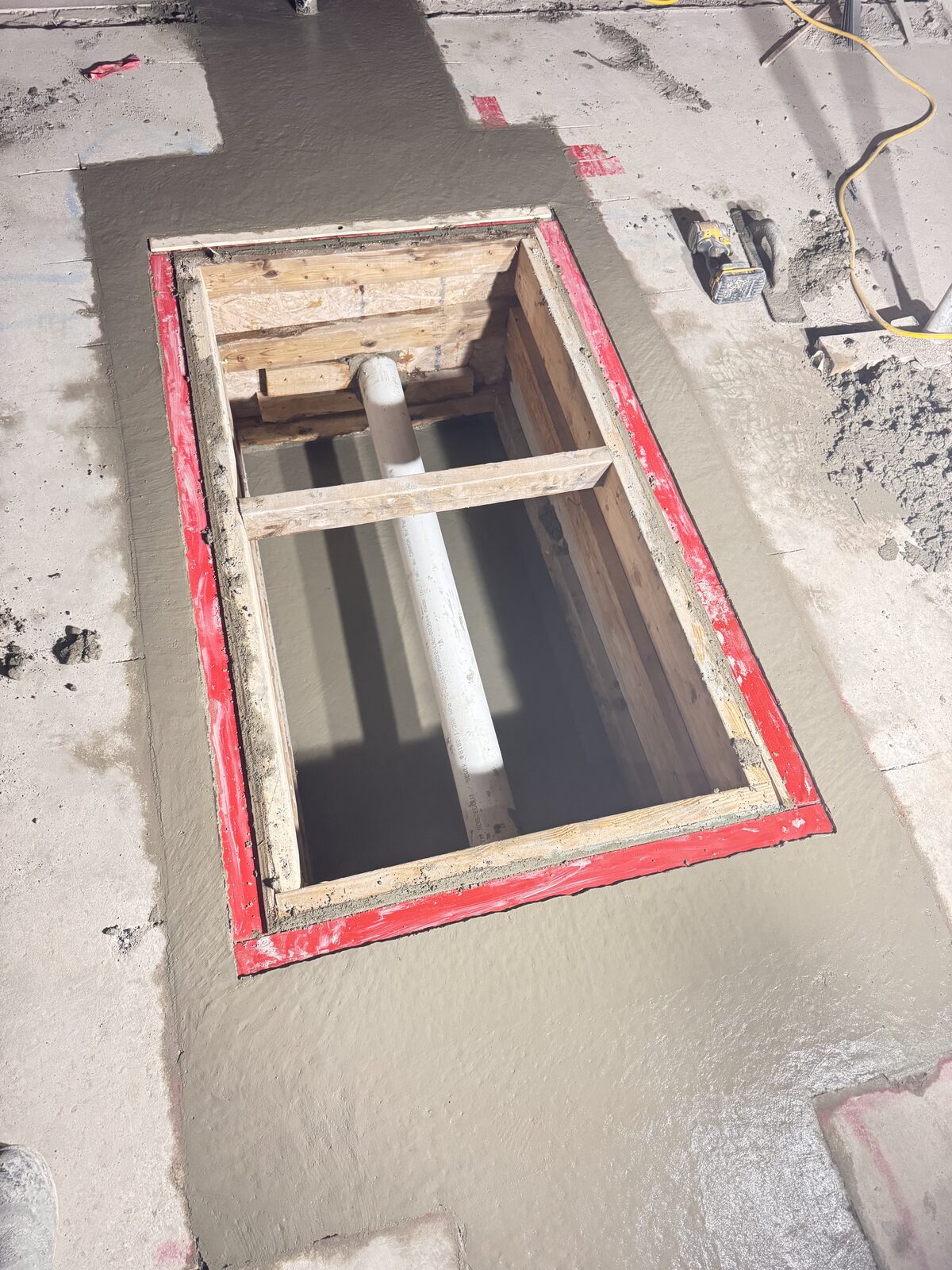 Fresh concrete pour around a framed opening with pipe for foundation work