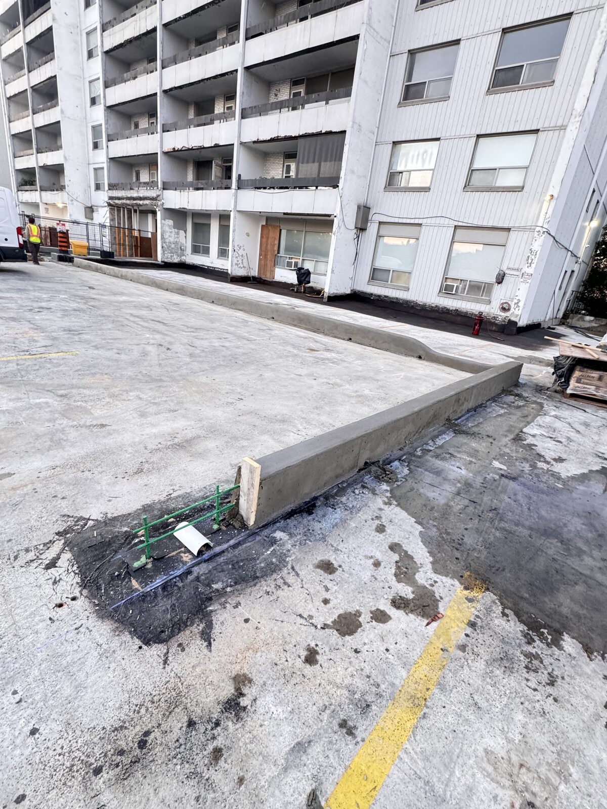 New concrete curb laid with rebar reinforcement in apartment building parking lot.