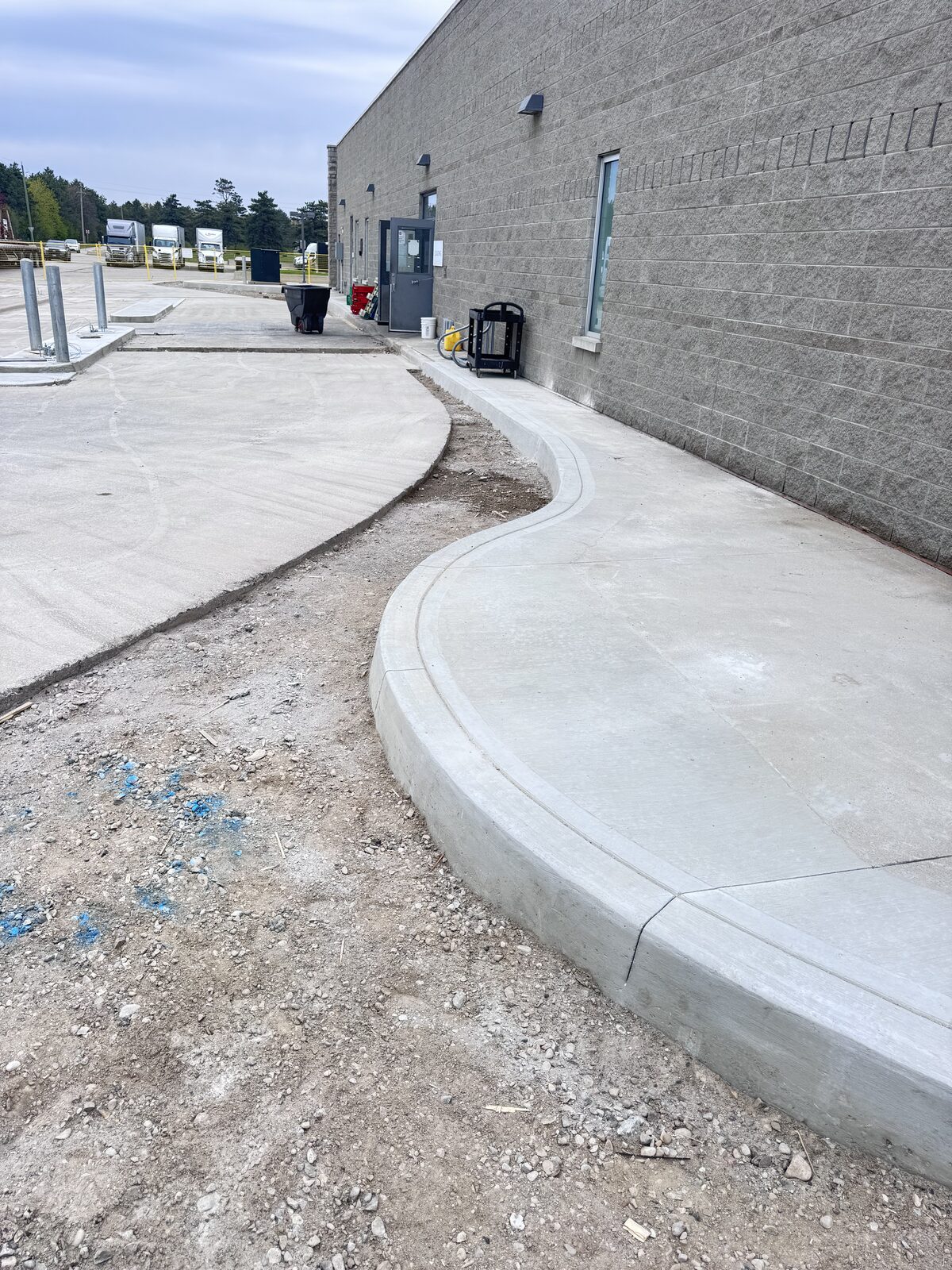 New concrete walkway with curves and curbs along a building