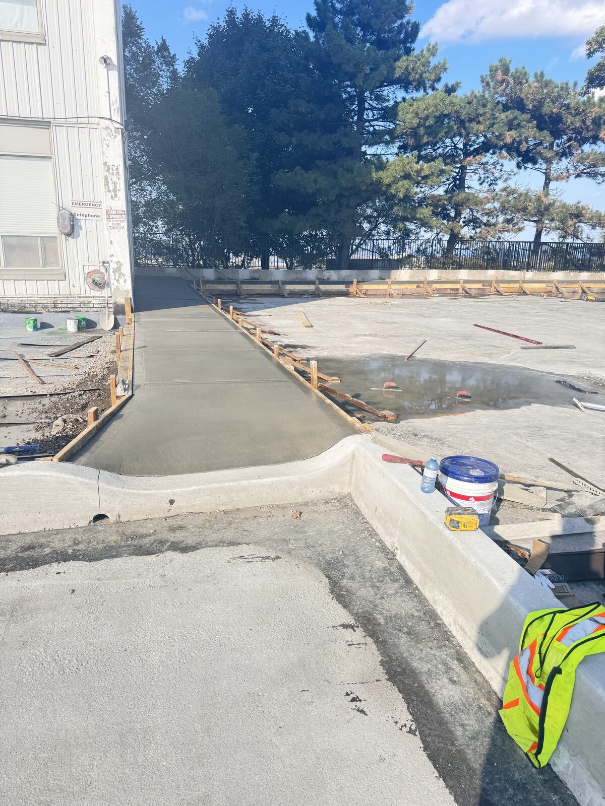 New concrete walkway construction with wooden forms and unfinished surrounding area