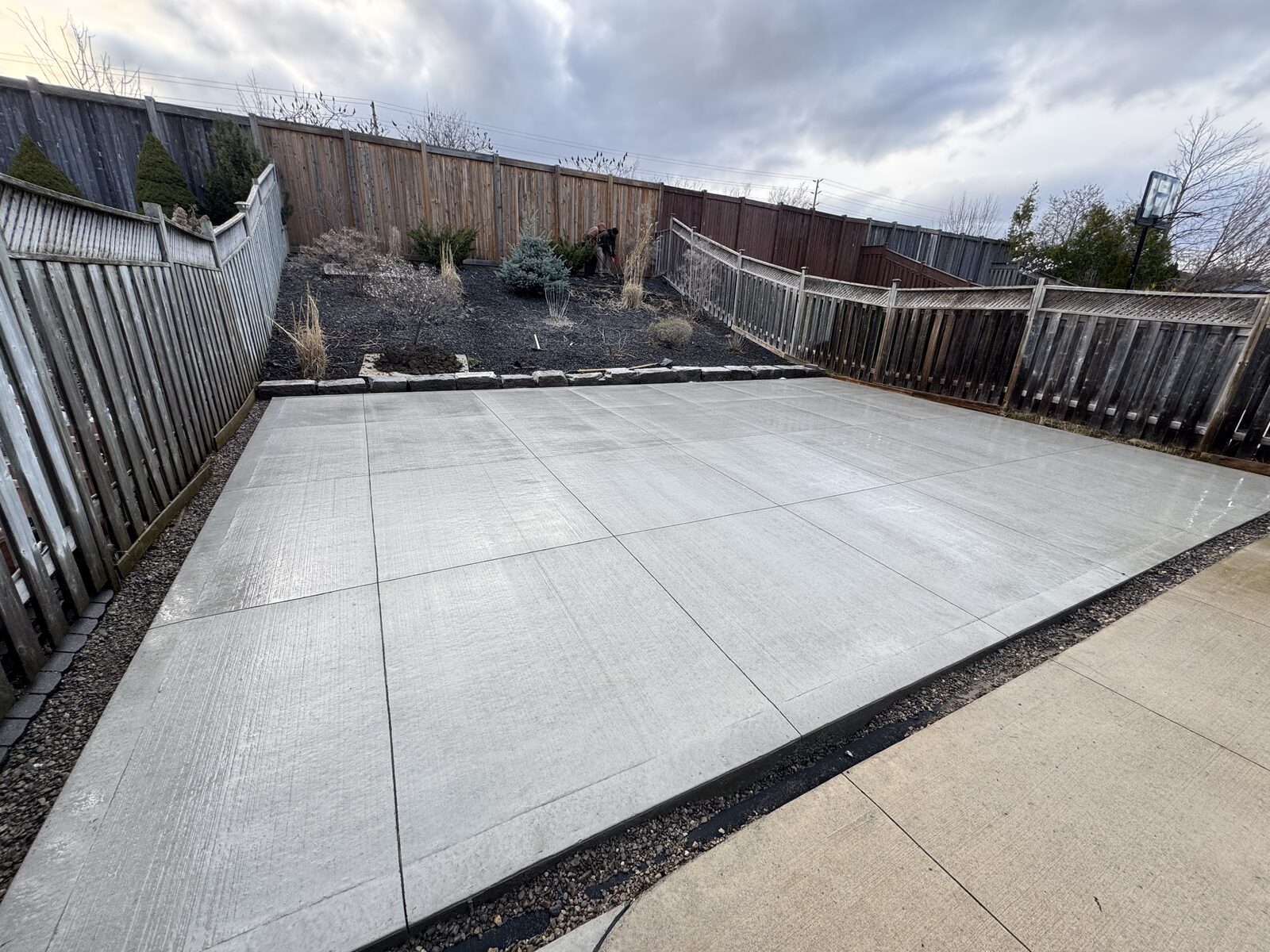 Newly poured concrete patio with clean geometric lines and stone border