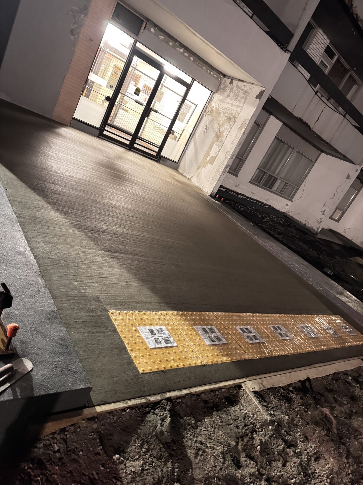 Newly poured concrete walkway with tactile paving at entrance