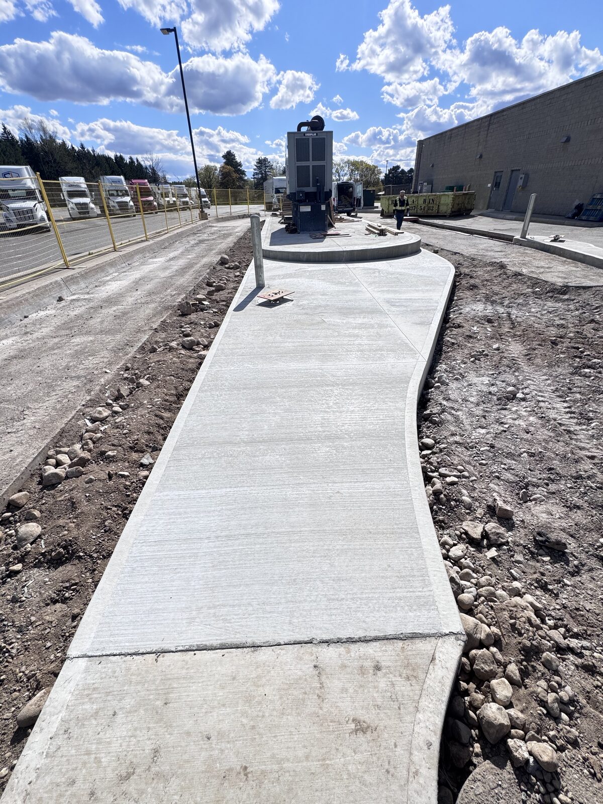 Newly poured curved concrete walkway in industrial setting