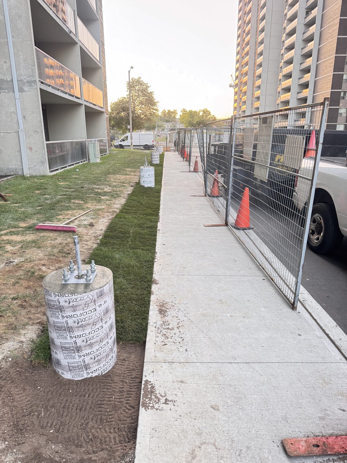 New concrete foundation forms are prepared for pouring next to a sidewalk.