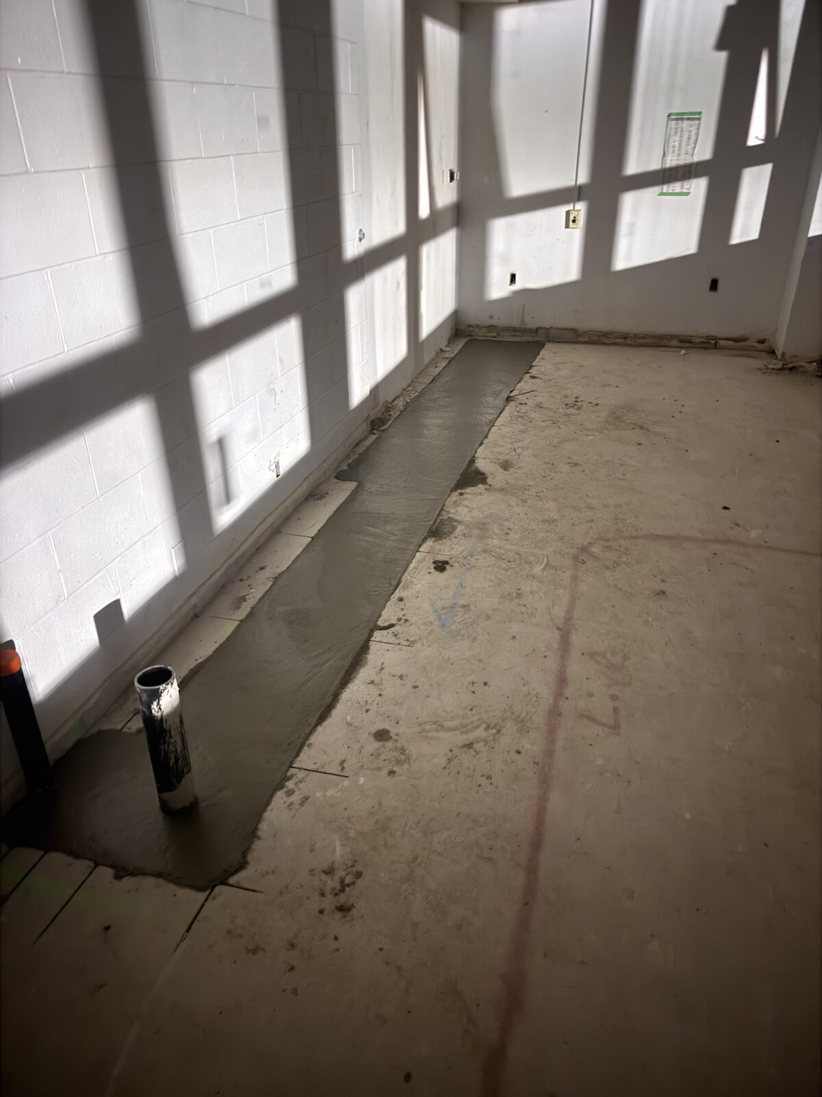 Fresh concrete pour along a wall in a construction zone.