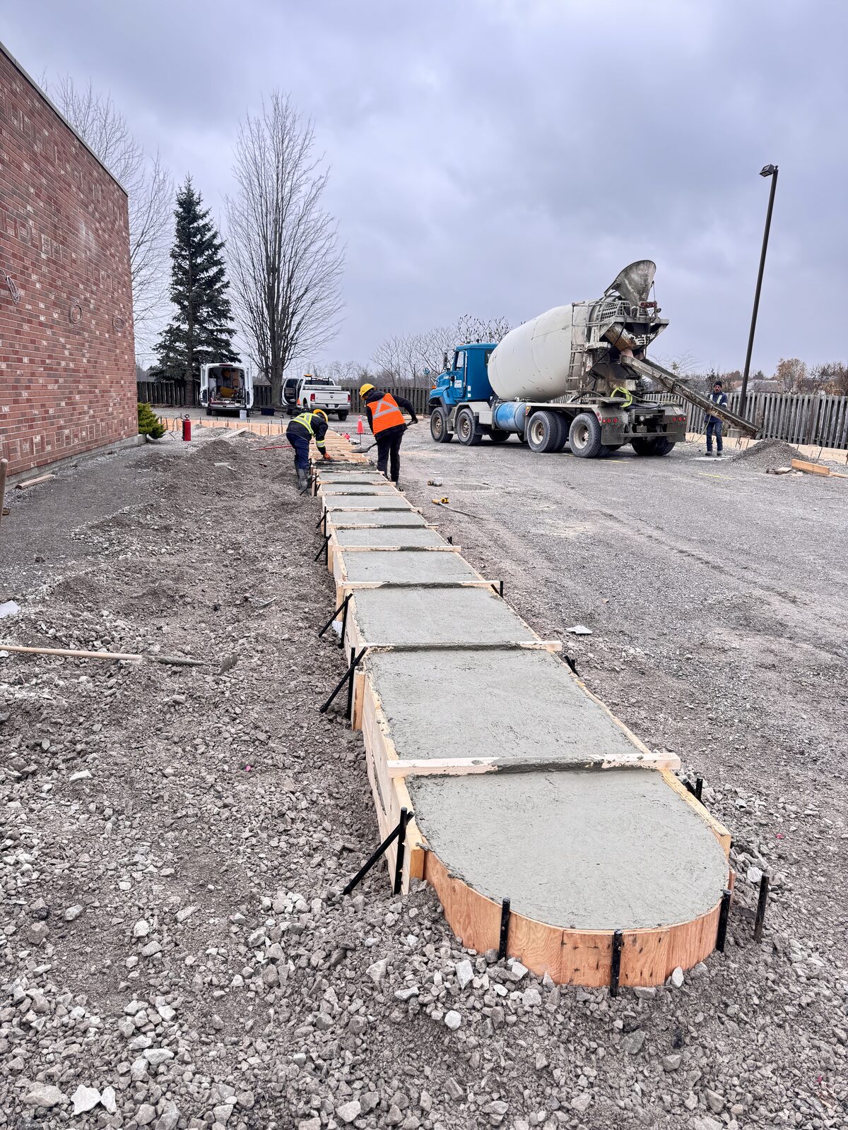 Crew pouring concrete for a new walkway with curved formwork
