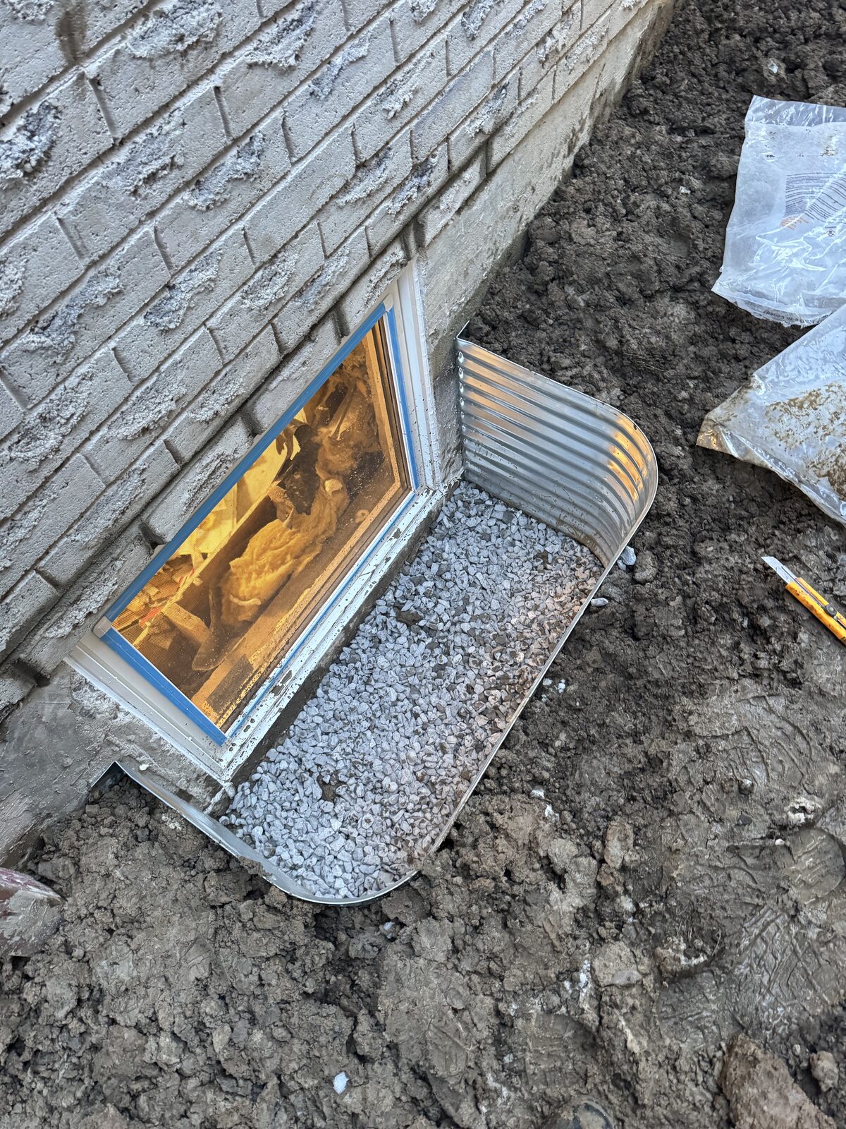 Window well installation with gravel drainage around egress window
