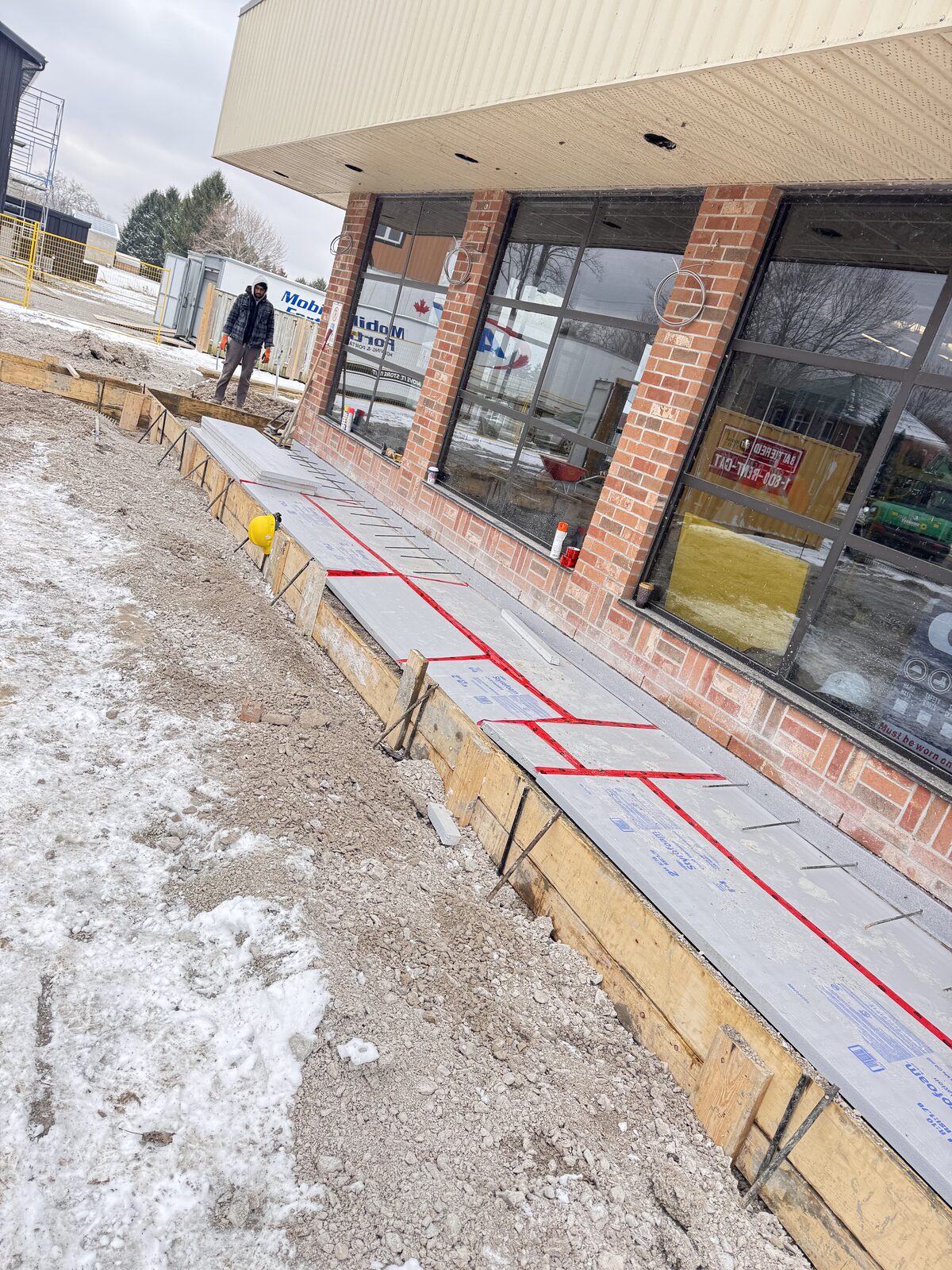 New concrete walkway forms being prepared next to a commercial building.