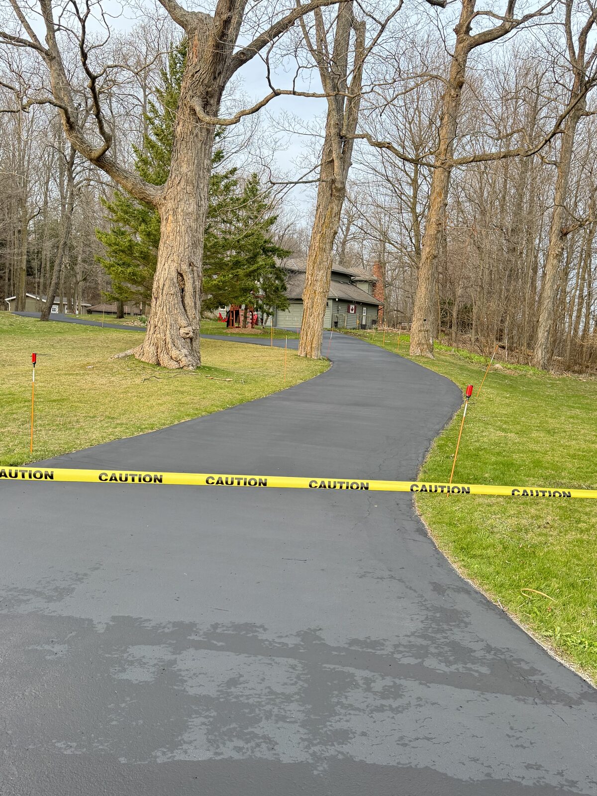 Freshly paved asphalt driveway leads to a residential home