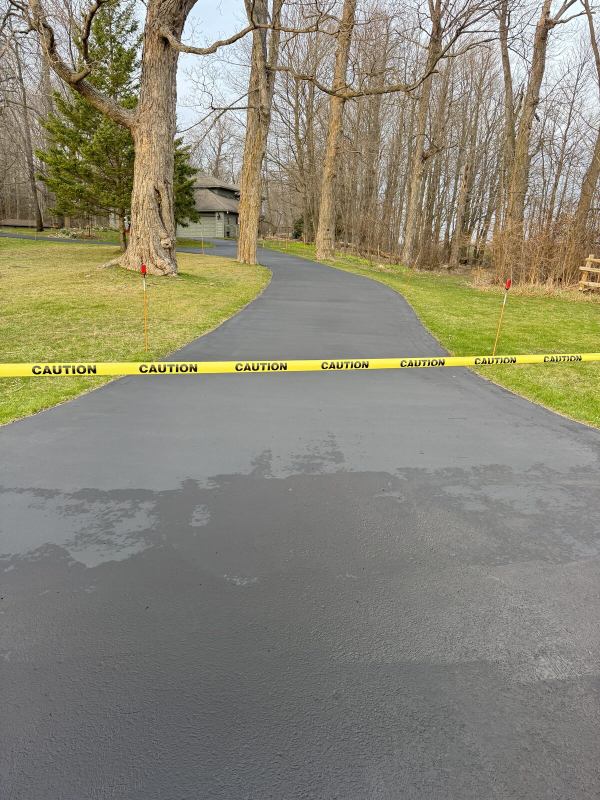 Curving asphalt driveway with caution tape across it