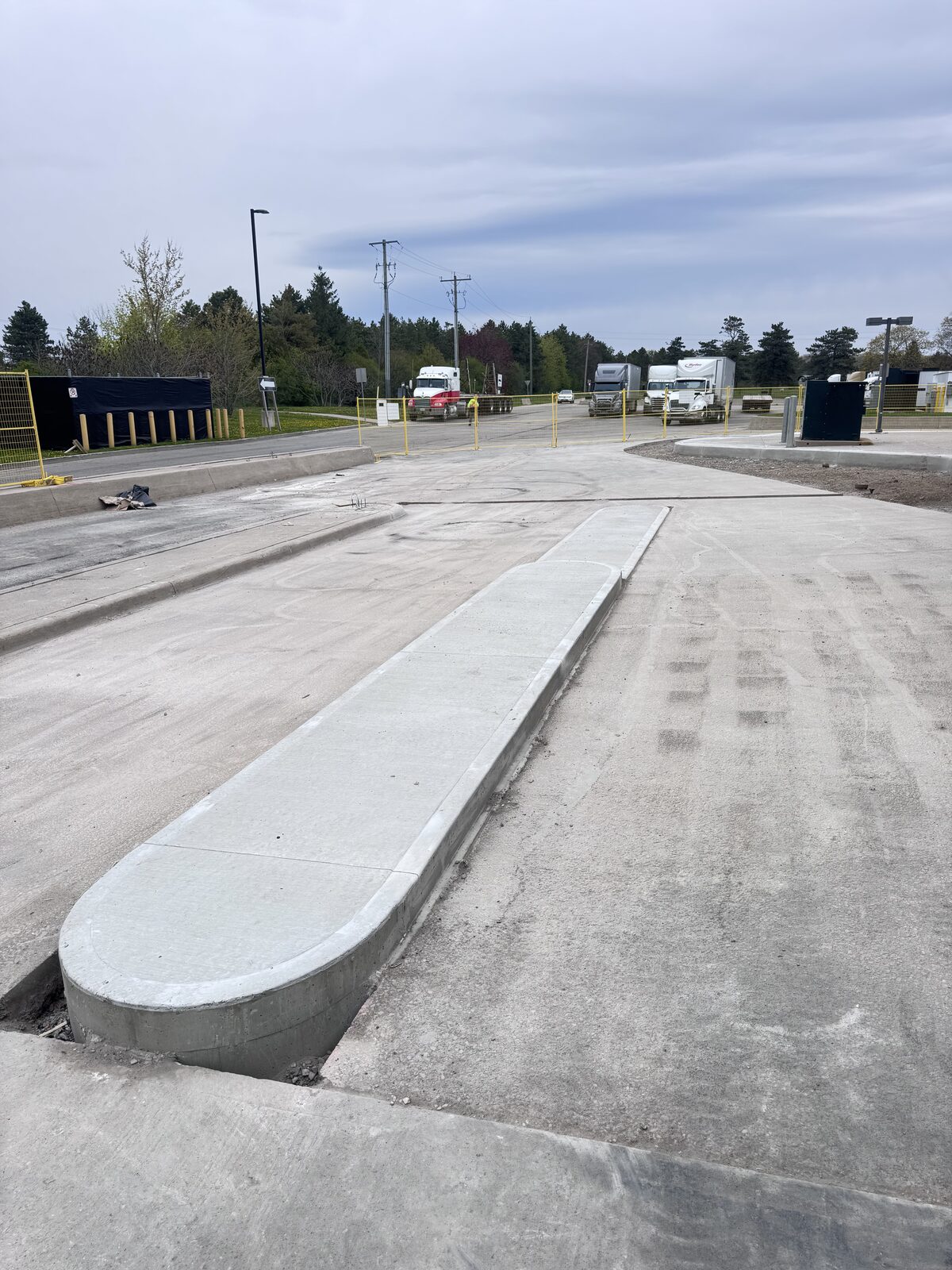 New concrete construction at a commercial site with trucks in background.