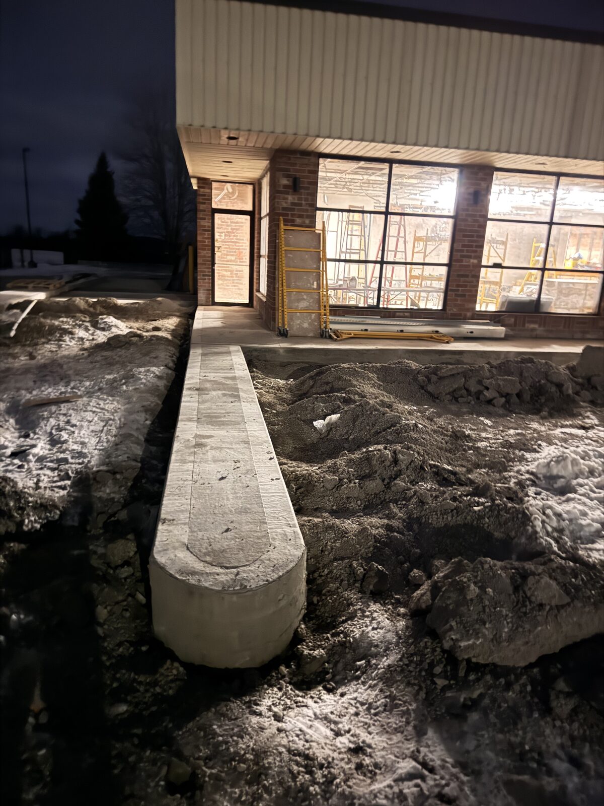 Curved concrete foundation edge next to a building construction site.
