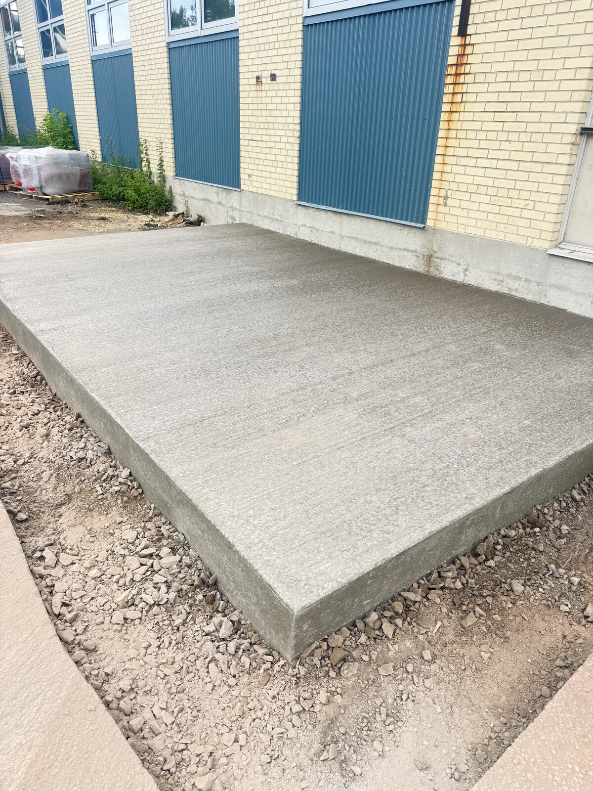 Freshly poured concrete foundation along a commercial building.