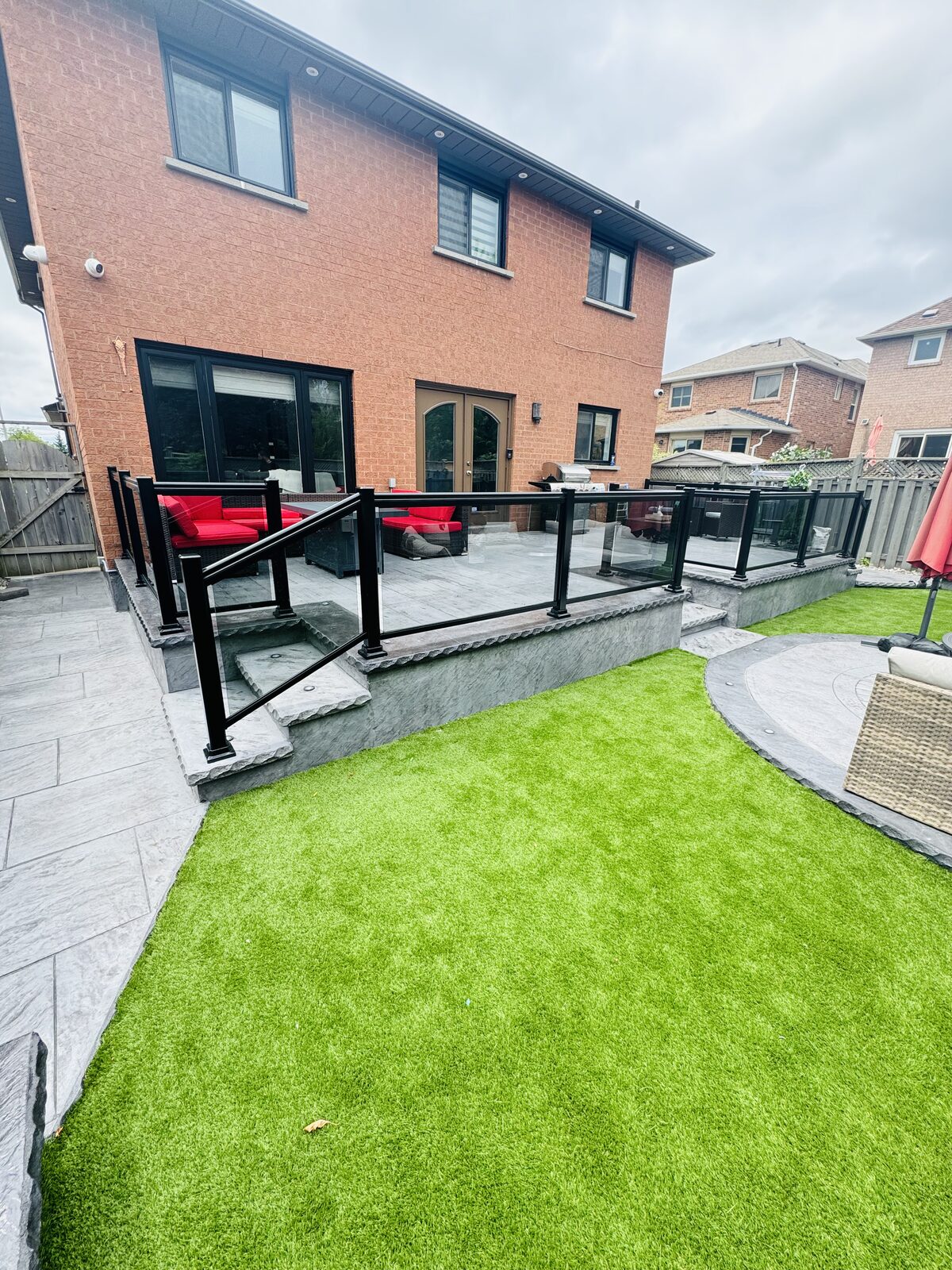 Modern concrete patio with glass railings and surrounding landscaping.