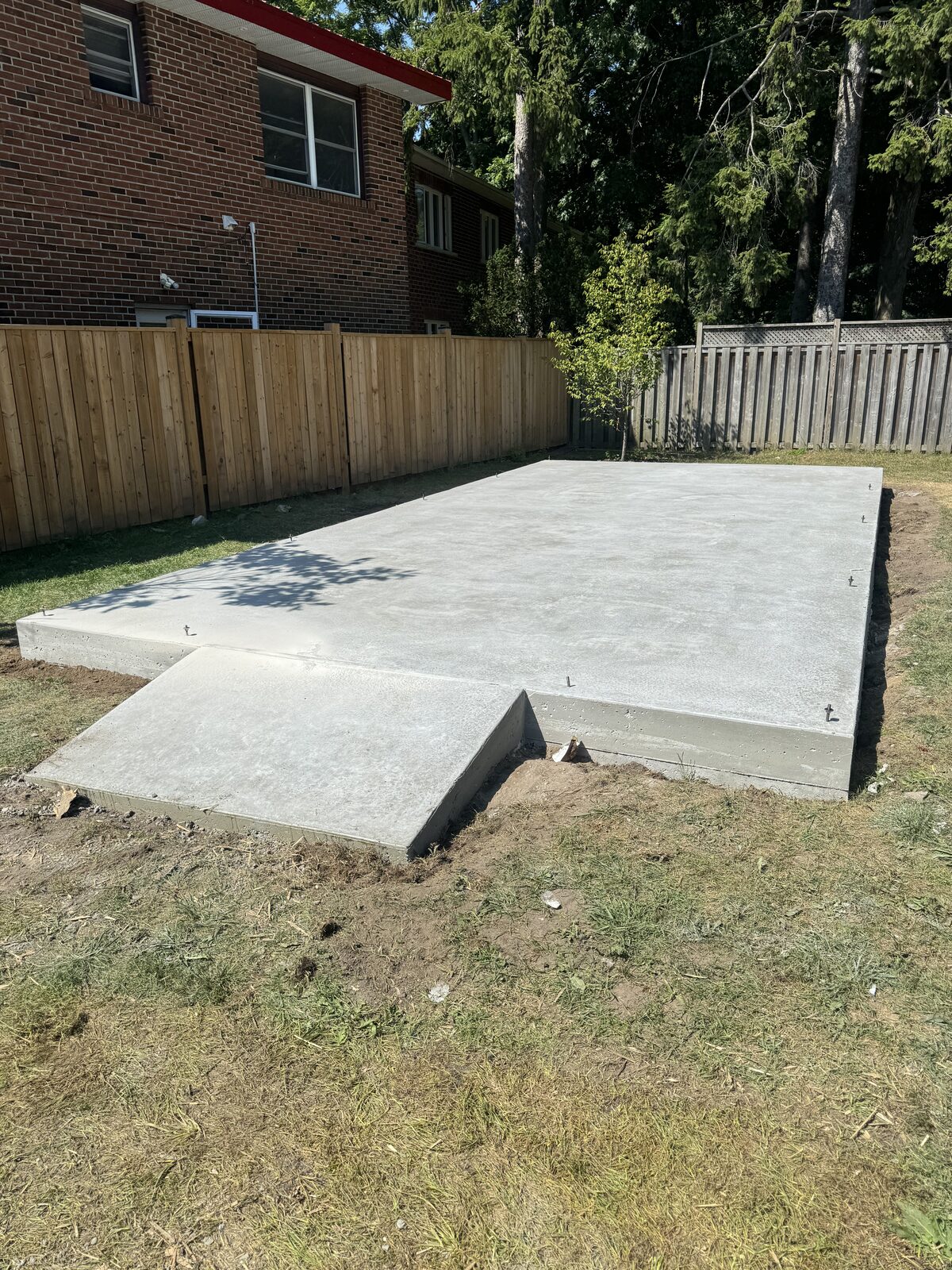 Newly poured concrete foundation with a ramp in a residential backyard