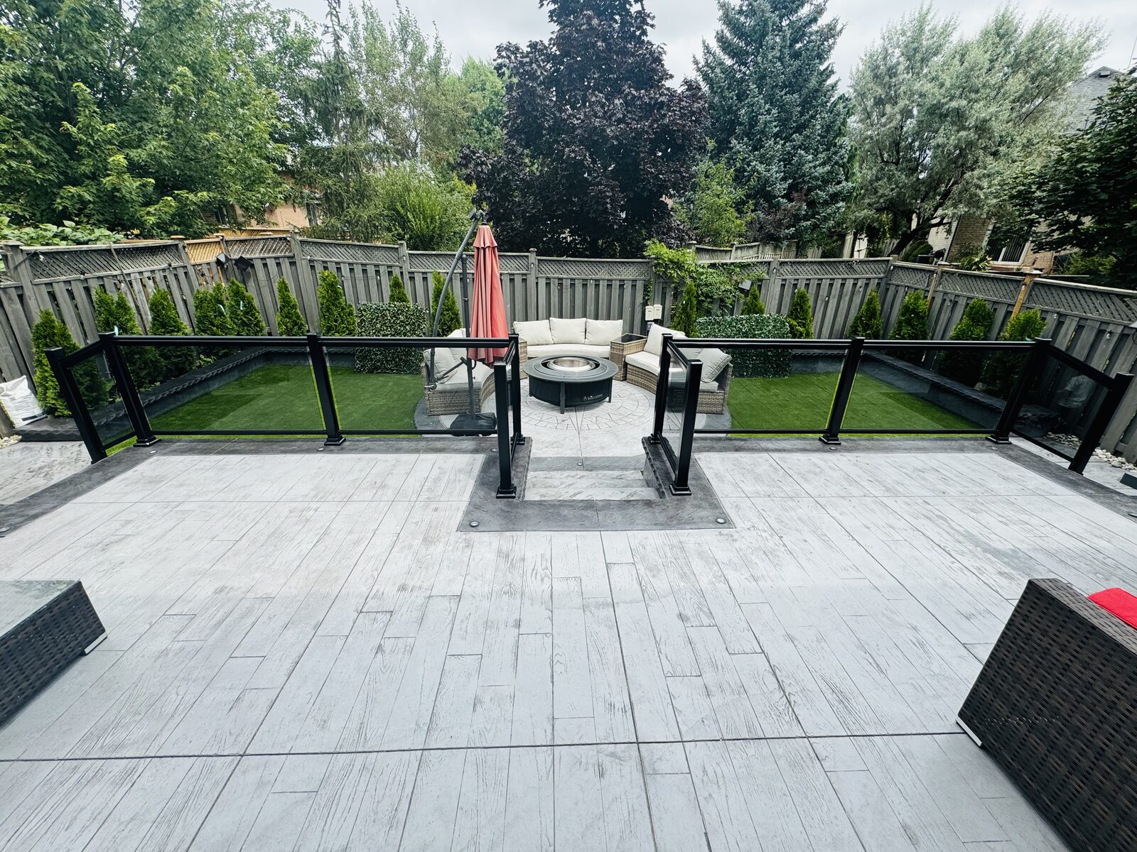 Stamped concrete patio with a circular fire pit and faux grass area
