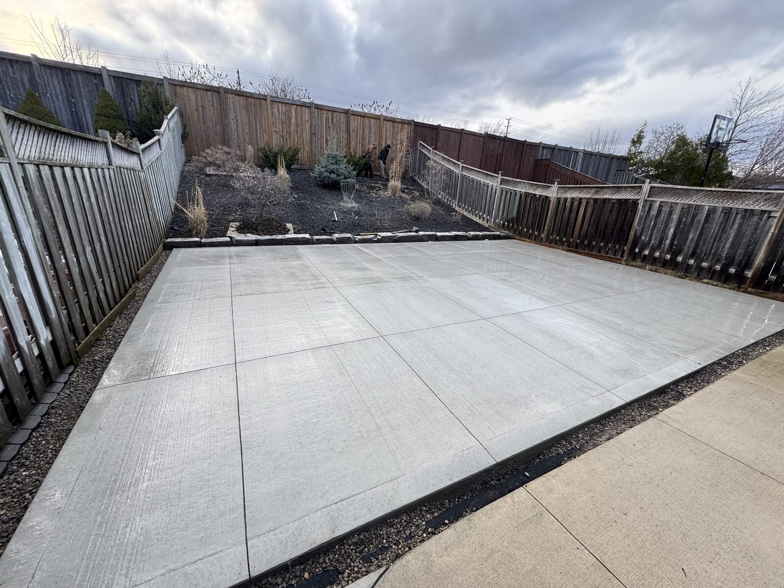 Newly poured square concrete patio with a textured finish in a backyard
