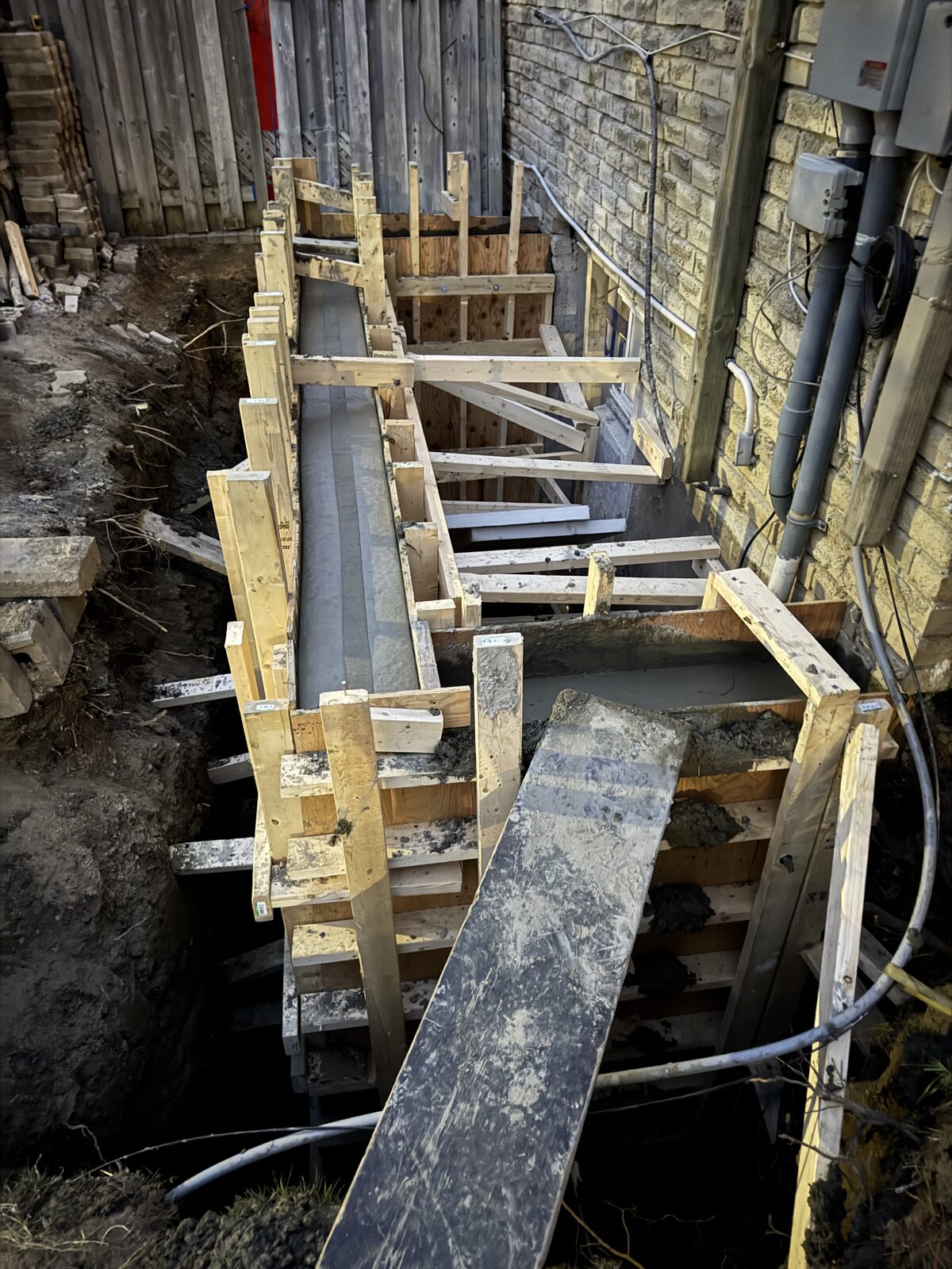 Newly poured concrete foundation walls with wooden formwork in progress.