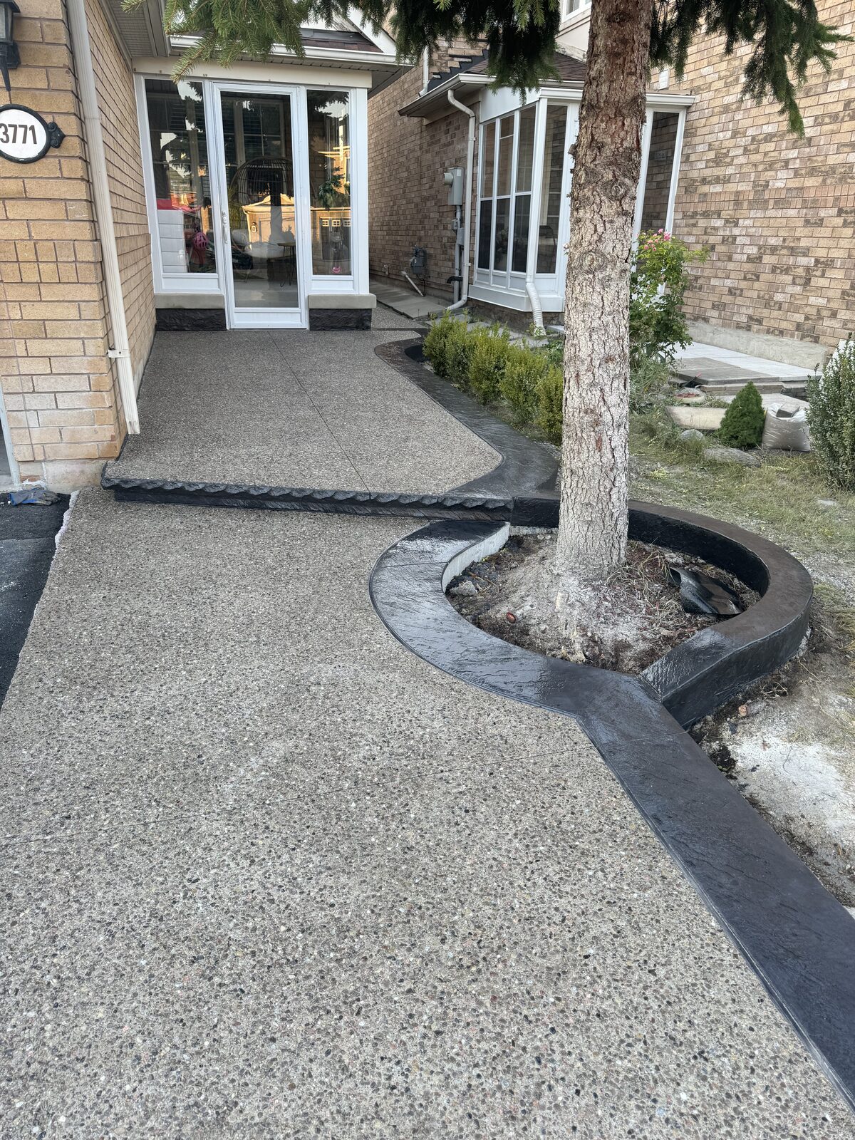Exposed aggregate walkway with stamped decorative border around tree.