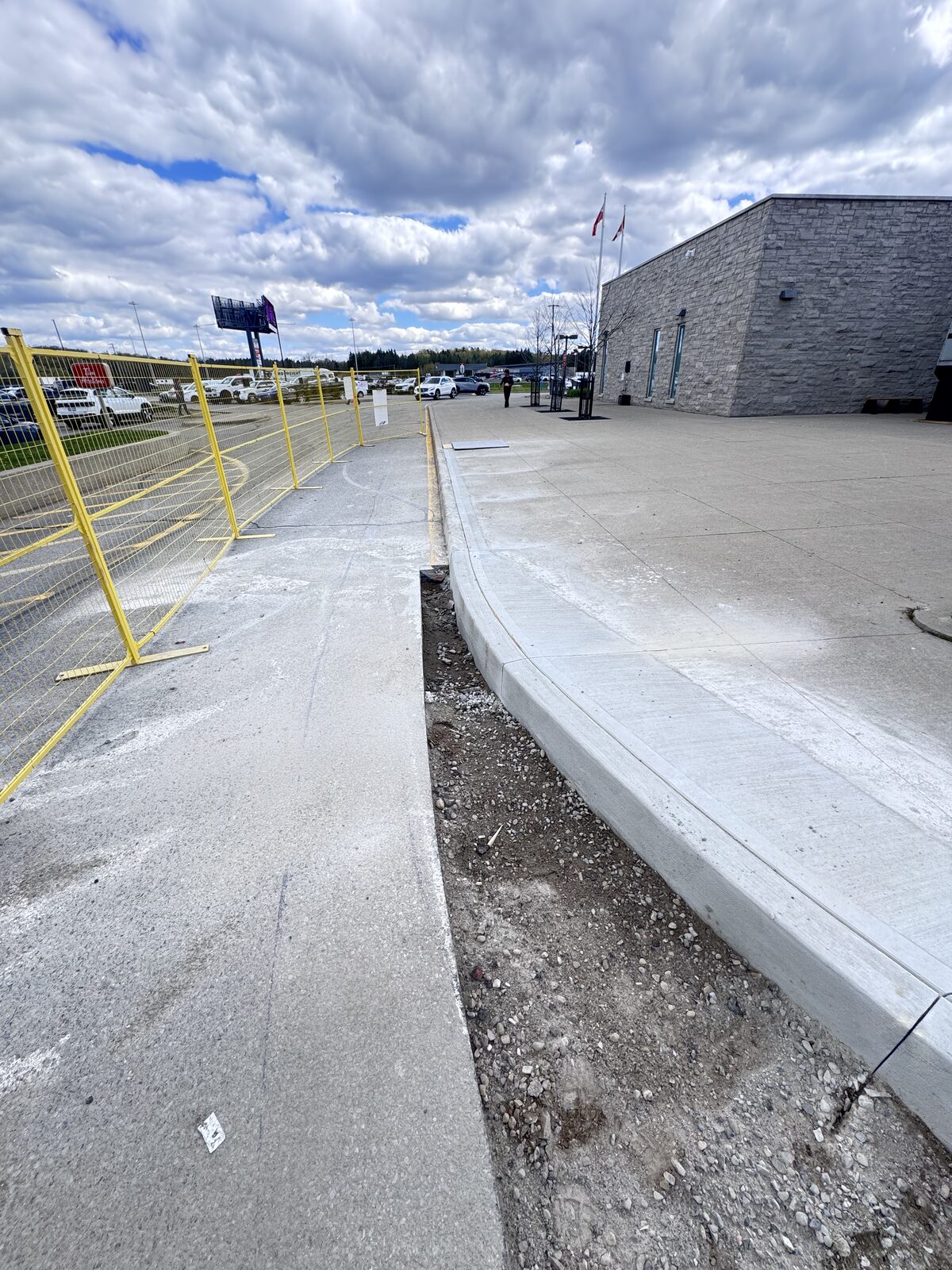New concrete curb and walkway construction adjacent to building