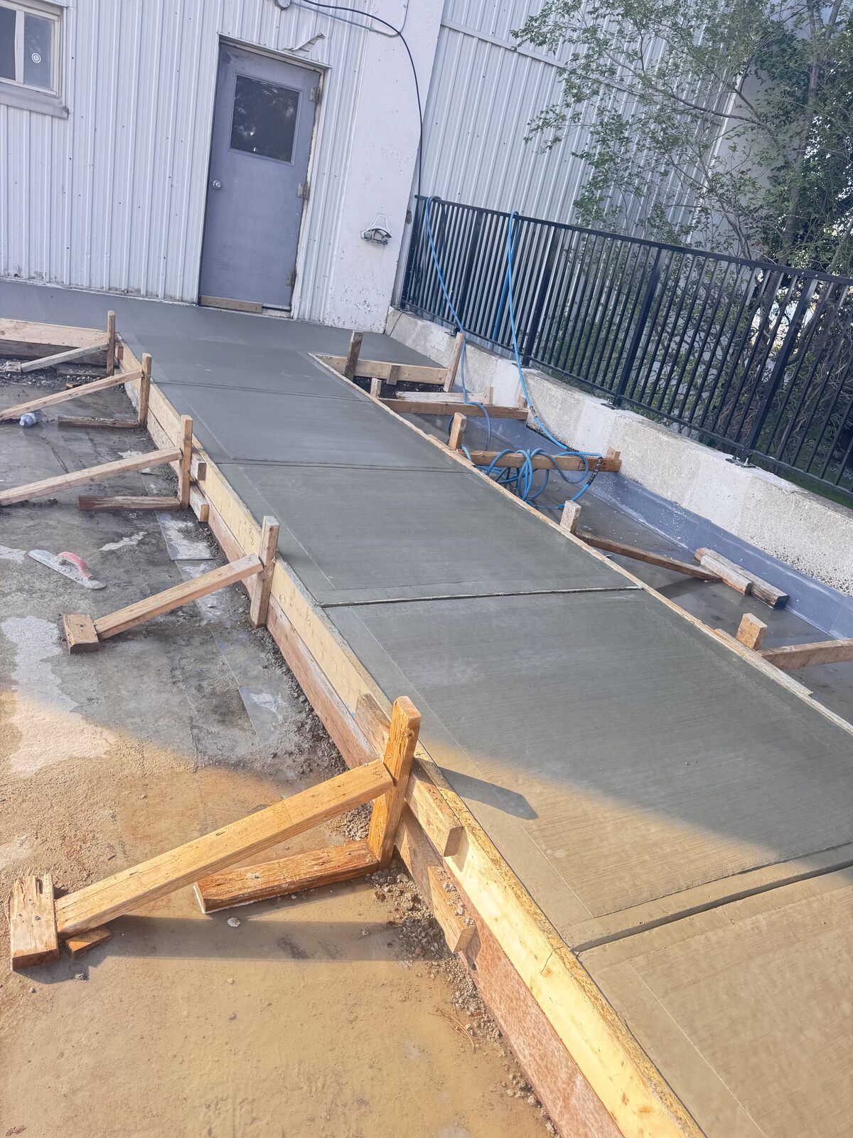 Concrete walkway construction with wooden forms next to building
