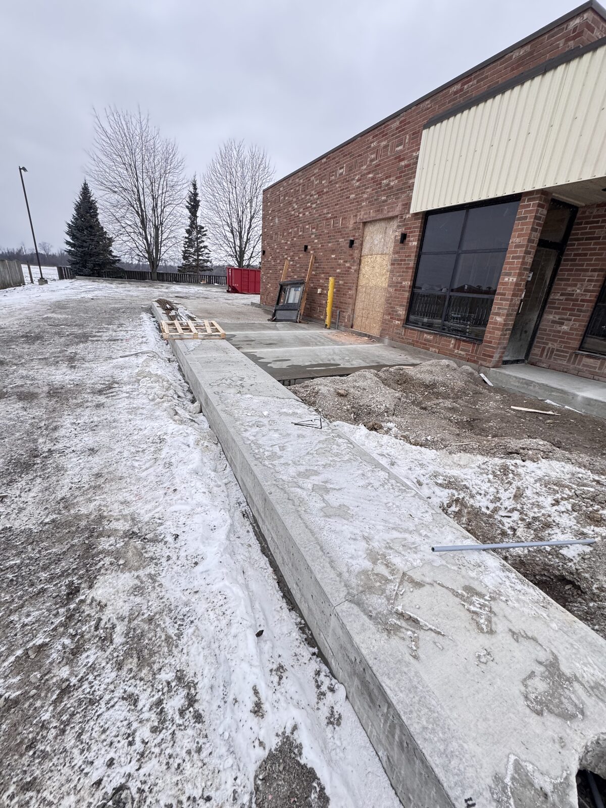 New concrete foundation wall construction beside a commercial building.