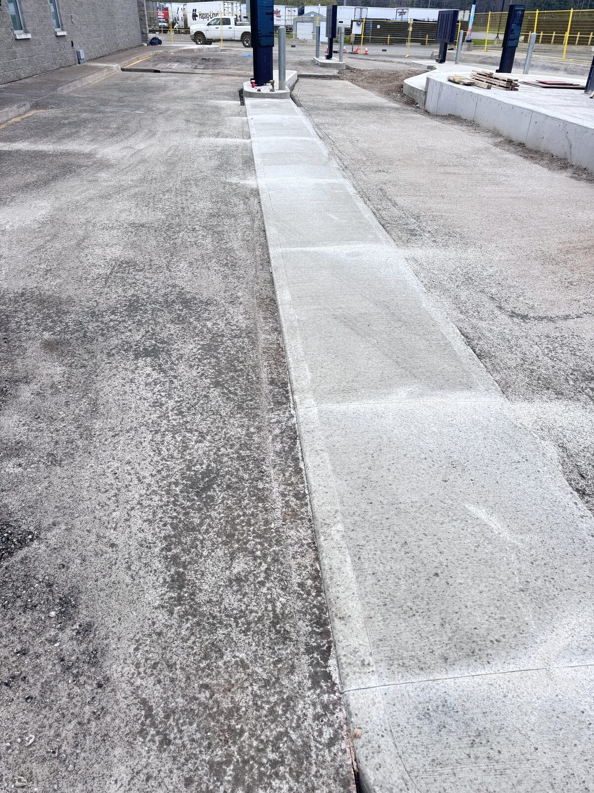 Newly poured concrete walkway next to an asphalt area