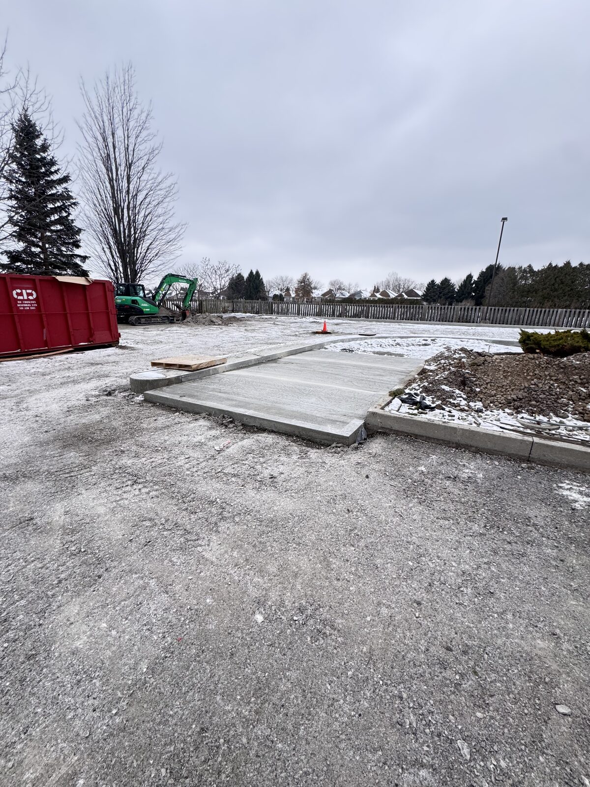 New concrete foundation being poured in winter conditions with excavator