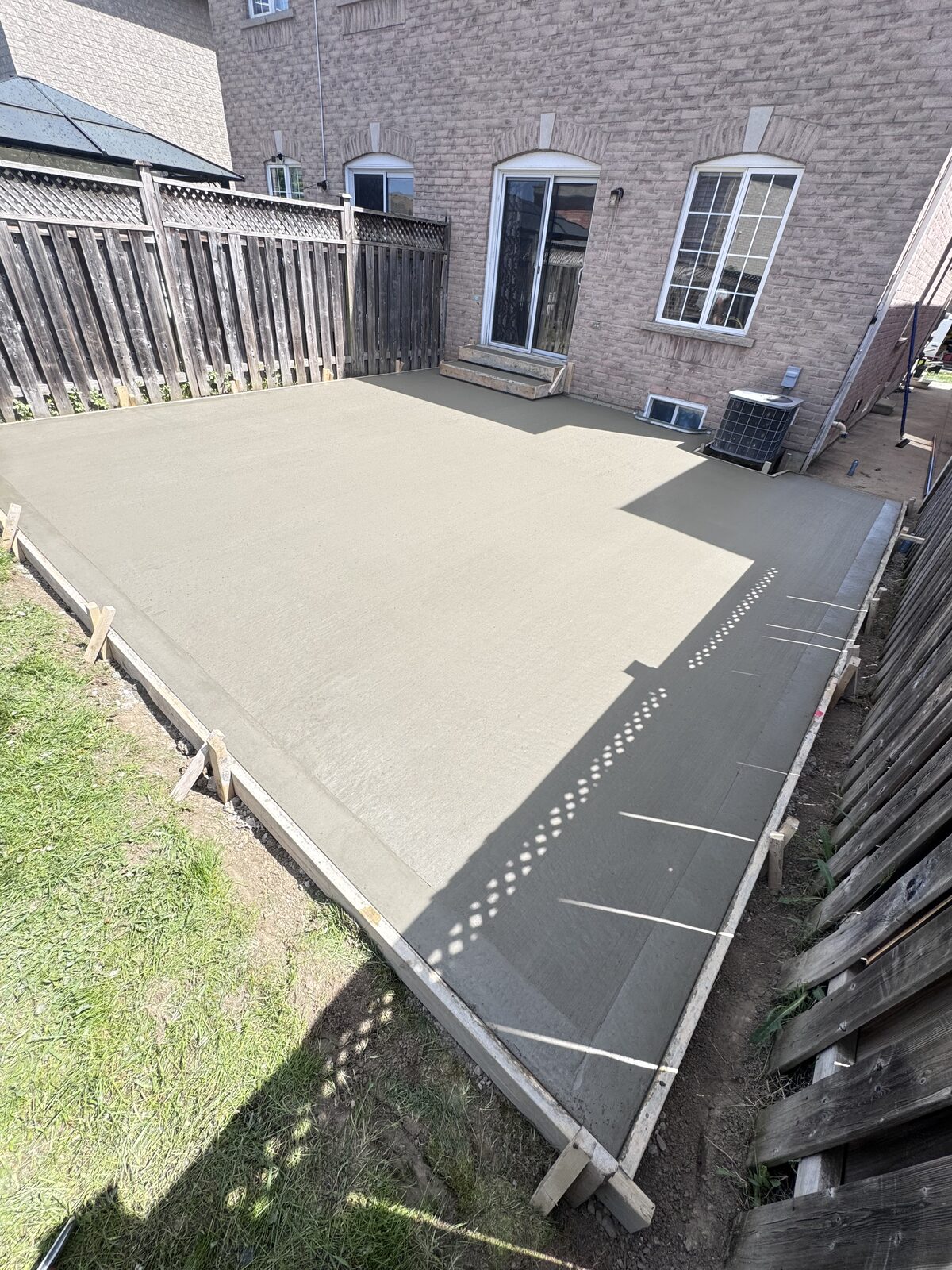 Freshly poured concrete patio adjacent to a residential home.